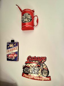 Trois plaques murales en métal : une avec l’inscription "Garage", deux en forme de bidons d’huile vintage, déco industrielle Pole Position