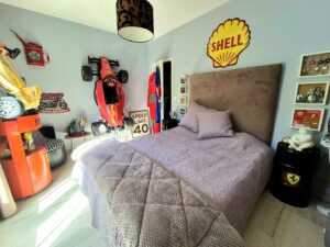 Vue d’ensemble du lit et de la chambre "Pole Position", ambiance immersive pour une nuit reposante et des rêves motorisés